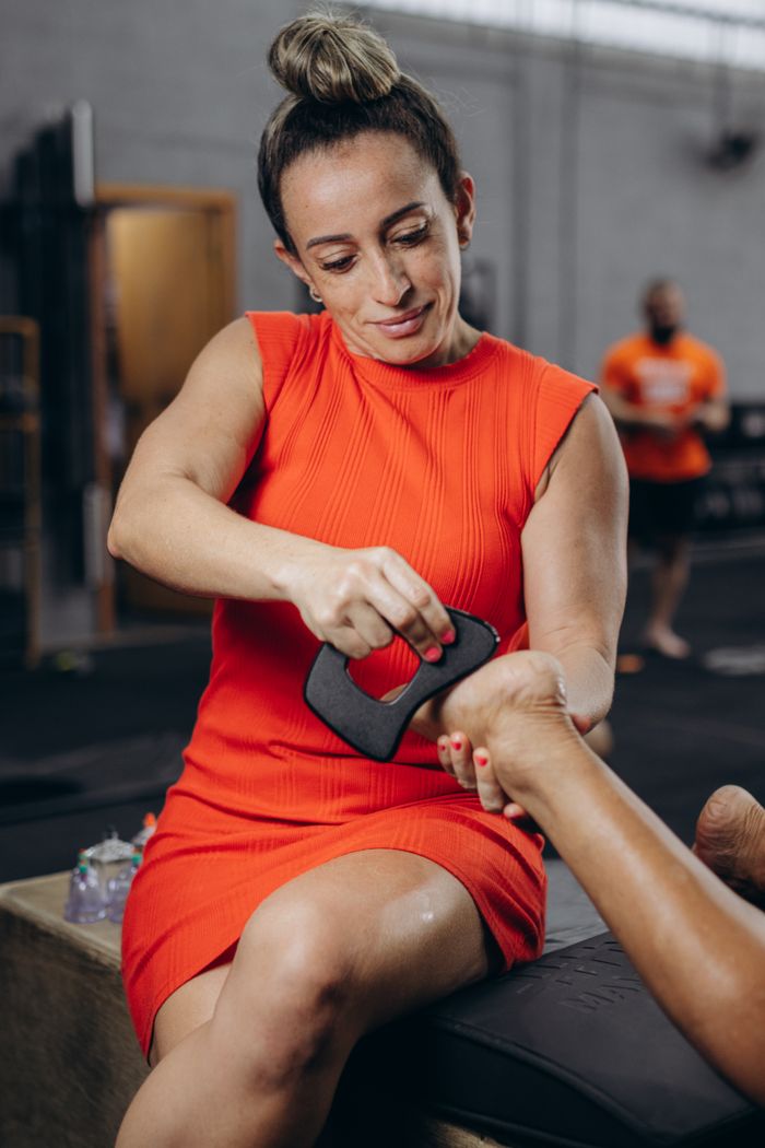 Crafting Captivating Headlines: Your awesome post title goes here Woman in a red dress performing a hand massage with a tool at a gym setting, promoting wellness.